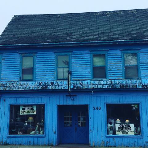 Dilapidated shop with sign 'Owner Retiring' in window.